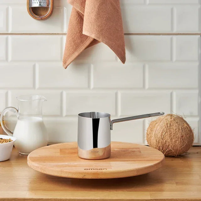 Emsan Aaron 500 ml stainless steel cezve pot on wooden board with milk, coconut, and kitchen towel in modern kitchen